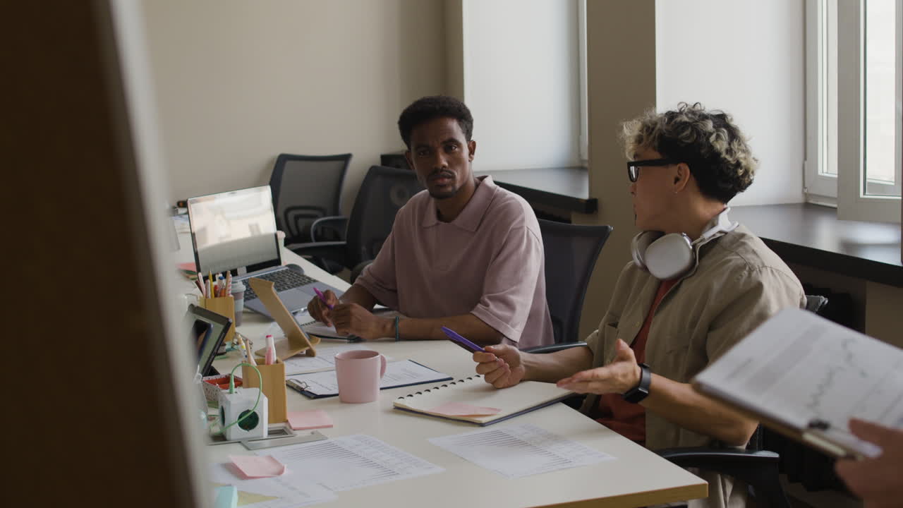 Two colleagues engaged in a discussion during an office meeting