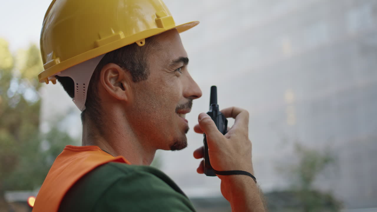 Building chief speaking wireless device at city closeup. Man using walkie-talkie