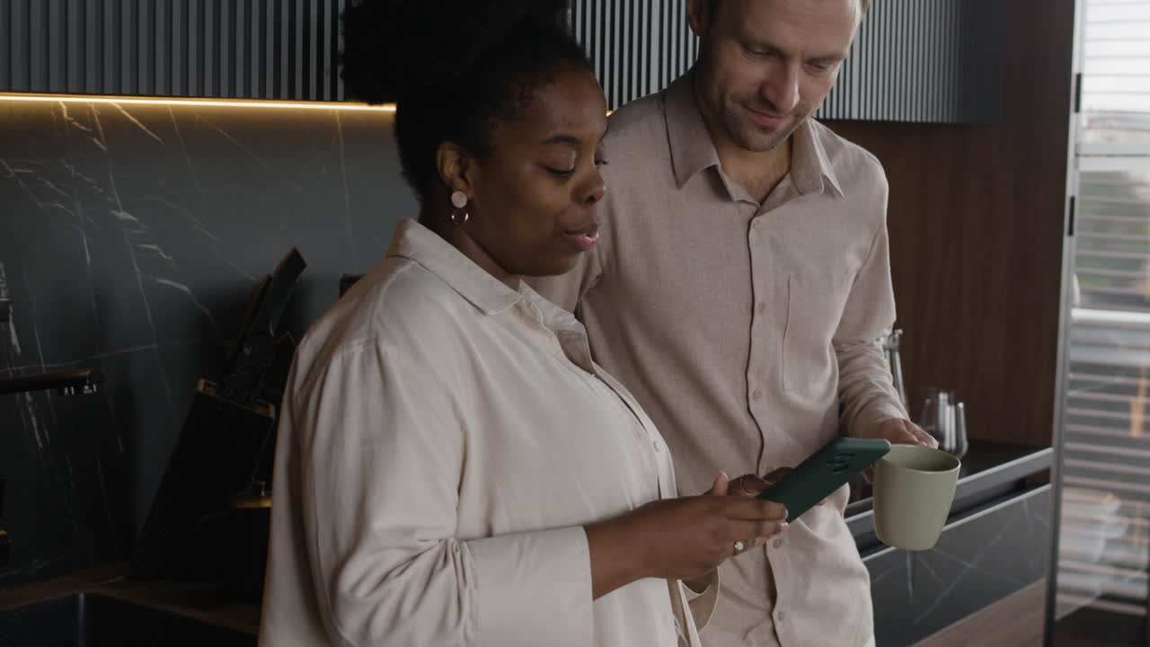 Interracial Couple in Kitchen Looking at Tablet Together
