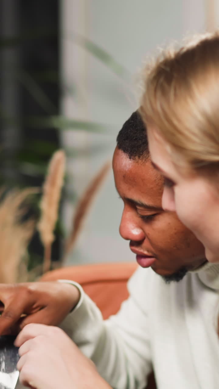 African-American man shows faded photo and tells about grandfather to white lady coworker in living room during visit closeup slow motion