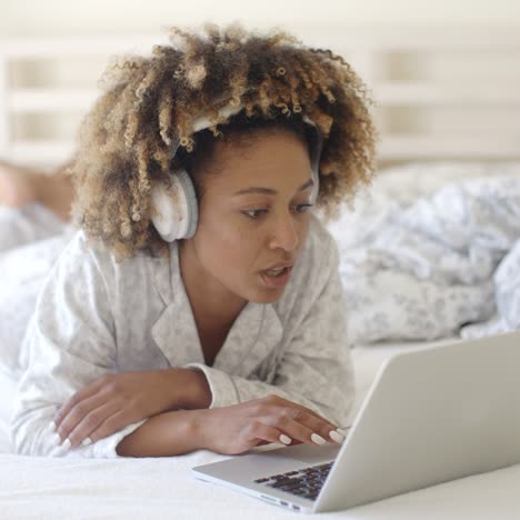 Mujer que usa su computadora portátil en cama