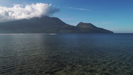 Mujer-Rubia-Con-Gran-Cuerpo-De-Pie-En-La-Playa-Blanca-Mirando-A-La-Isla-Camiguin,-Aérea