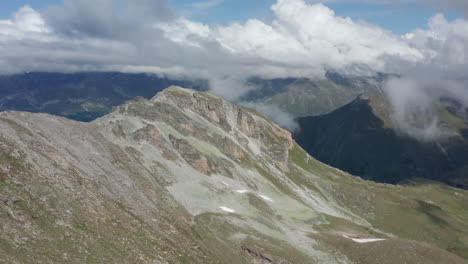 Antenne-Des-Hohen-Berggipfels-Mit-Wolken,-Die-Sich-Am-Himmel-Bilden