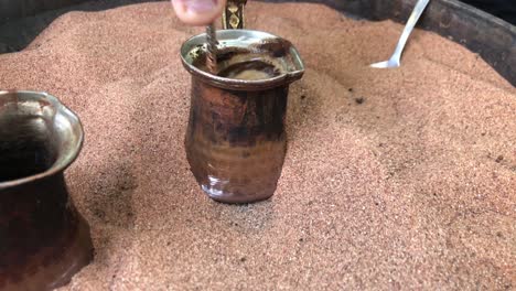 traditionally cooking coffee in hot sand in a coffeepot known as "cezve" in turkish, turkey.