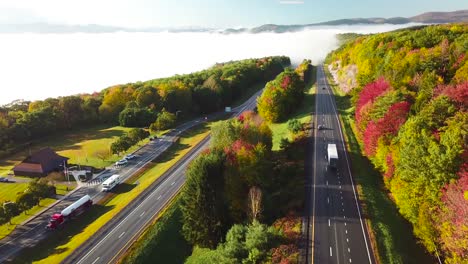 aerial of a semi truck traveling on a highway road through the fog in fall