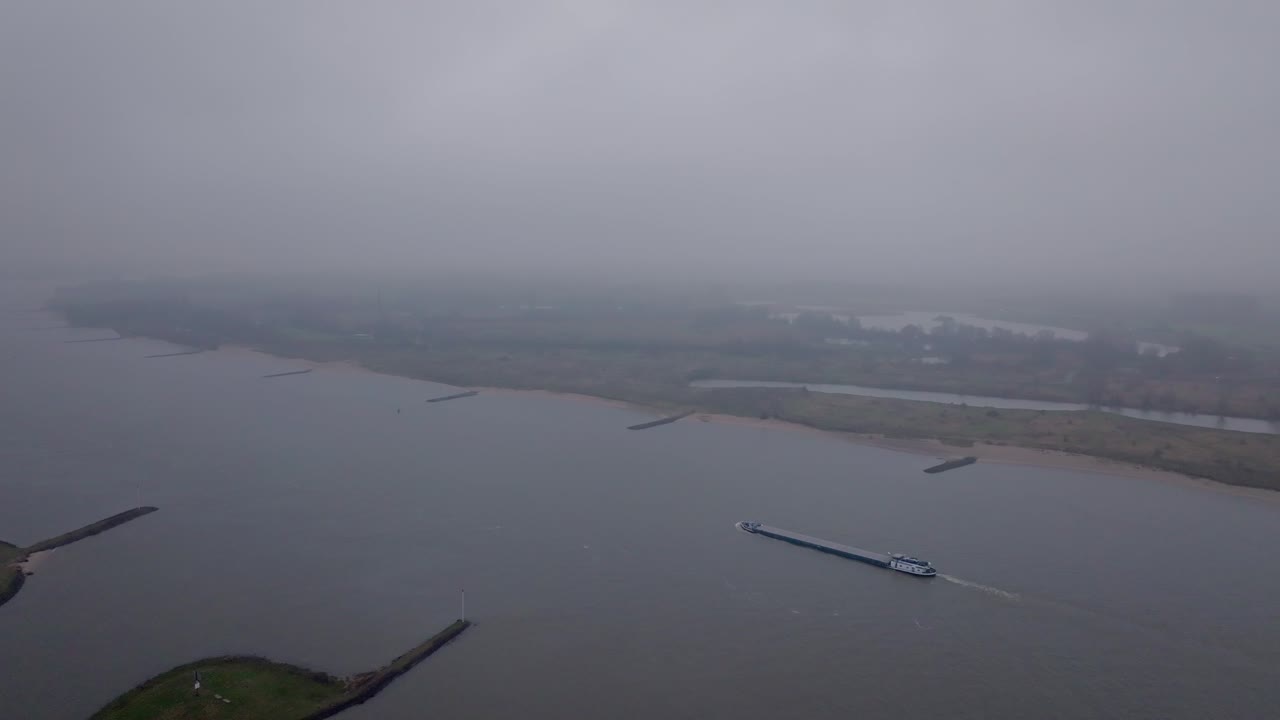 Drone shot of A Cargo ship on the Waal river during foggy conditions