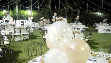 globos decorativos que mueven el viento atados a las mesas de una noche de bodas incluso antes de que lleguen los invitados