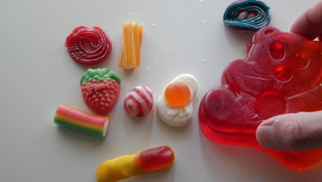 Closeup-male-hand-picking-colourful-assorted-jellies-on-a-table-in-studio-enviroment