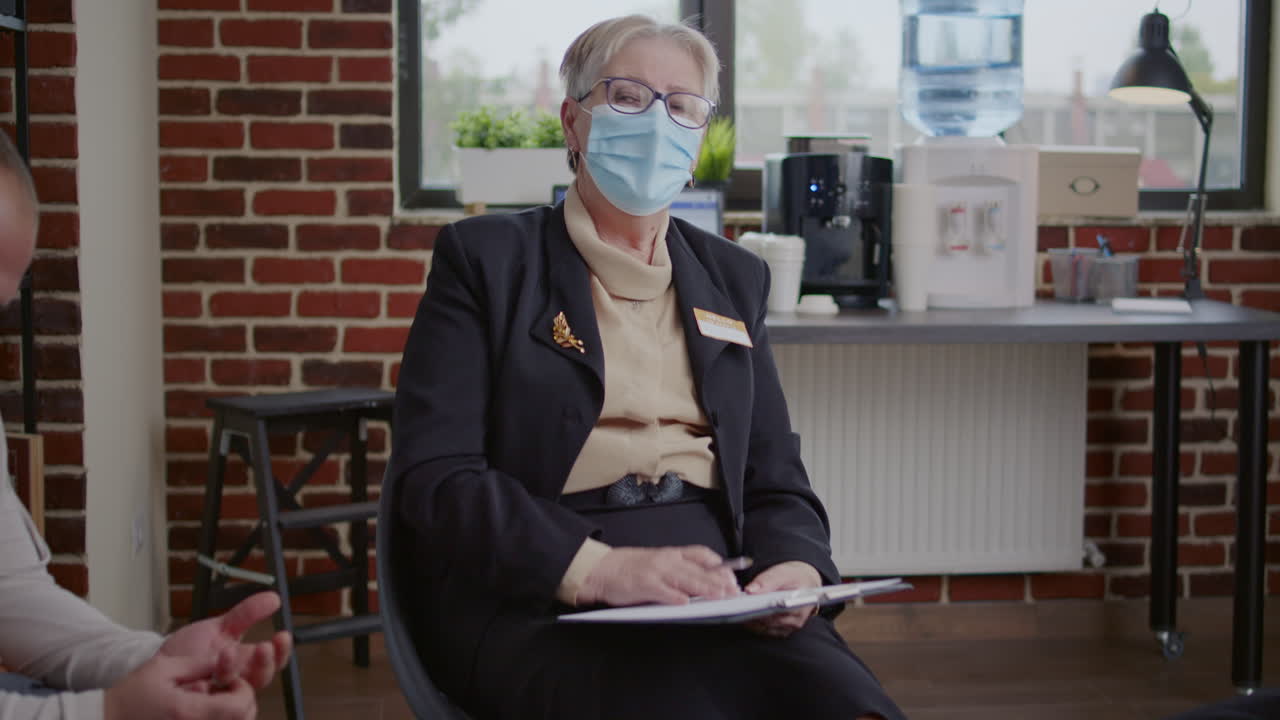 Psychotherapist talking to group of people at aa therapy meeting about recovery during pandemic