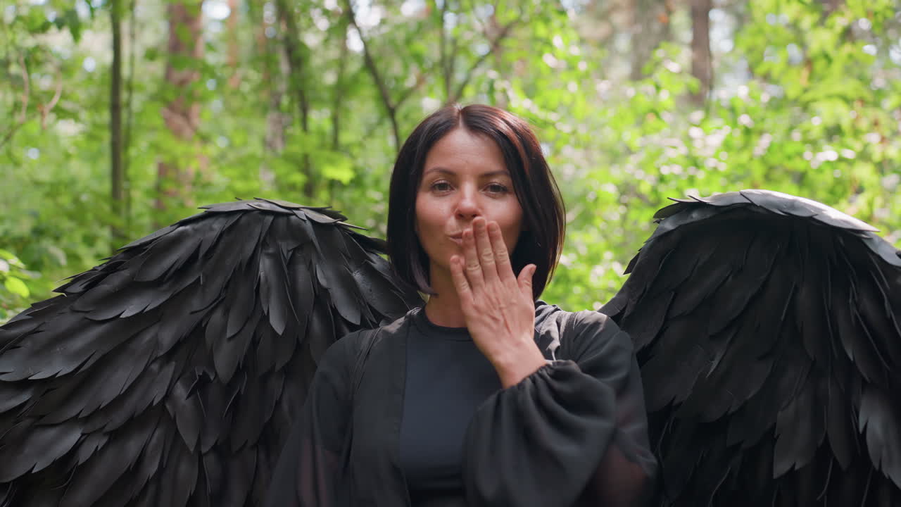 Close-up van een dame met een zwart verenpak die een zachte kus geeft met een vriendelijke glimlach onder het zonlicht in een groen bos, waarbij mysterie, charme en een fantasievolle sfeer worden gecombineerd met natuurlijke schoonheid