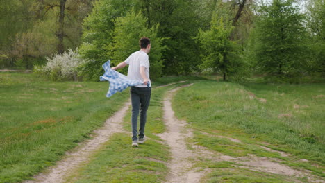 man walking on a path in a park with a plaid shirt