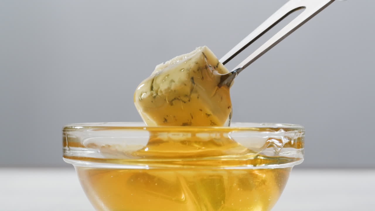 Tasty blue cheese with rosemary, honey and walnuts on white table, close up of Dorblu in cafe pouring in honey.