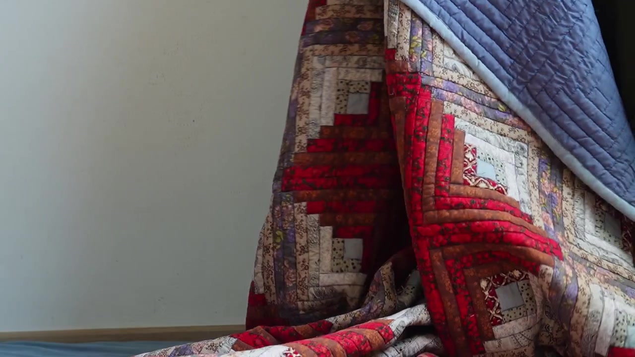 Mann handhabt traditionelle gemusterte Decke während der Schlafzimmerroutine