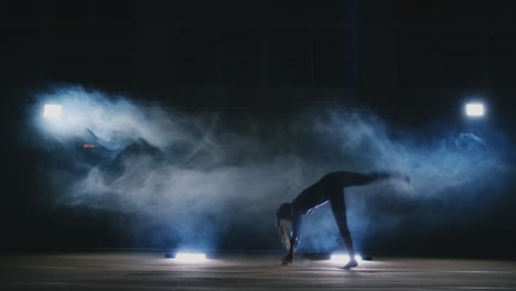 In-slow-motion-in-the-smoke-girl-acrobat-performs-several-back-flips-and-coups-in-the-air.