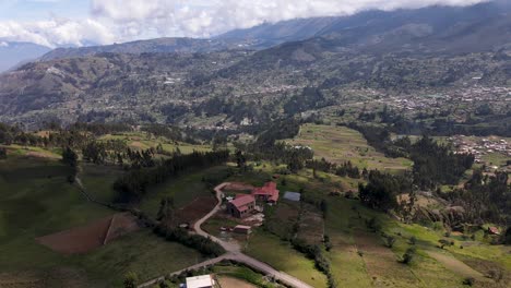 Revealing-drone-shot-of-a-small-house-located-on-top-a-hill-with-a-view-of-the-vast-green-hills-in-the-highlands-of-Peru