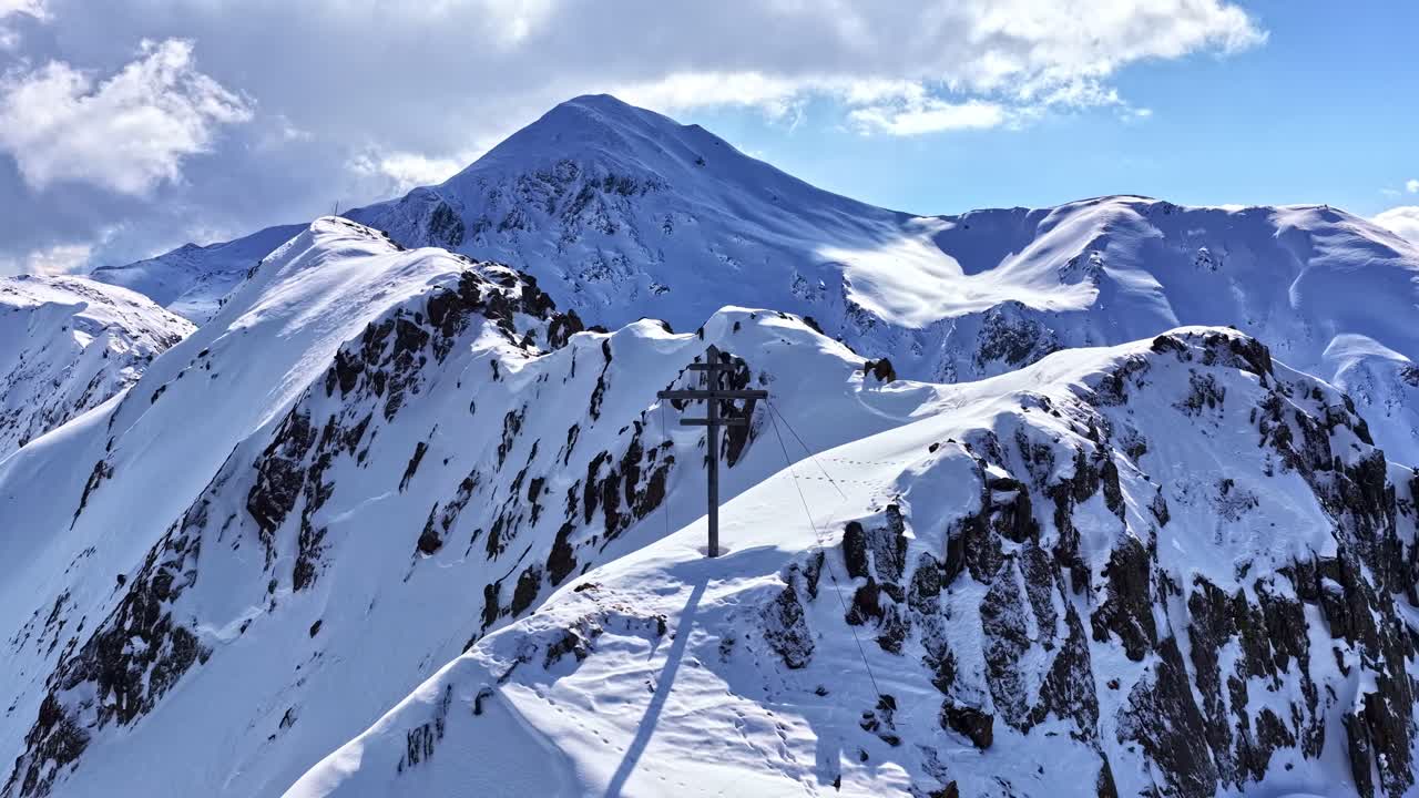 Vista panoramica di cime montuose innevate con torre e cavi di una funivia, paesaggio per il turismo invernale