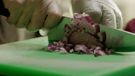 el chef cortando hábilmente la cebolla roja en la tabla de cortar verde
