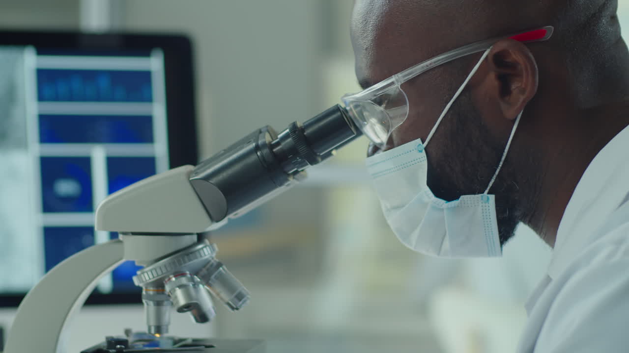 African American Scientist in Mask Using Microscope