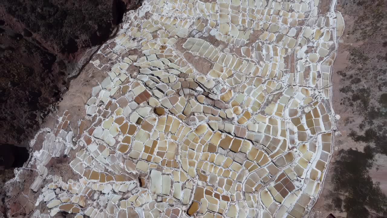 High angle establishing of the ancient Salineras de Maras salt pans cascading down the mountains
