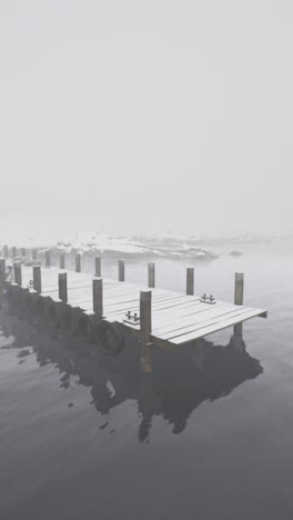 misty winter morning at a dock on a quiet lake surrounded by snow