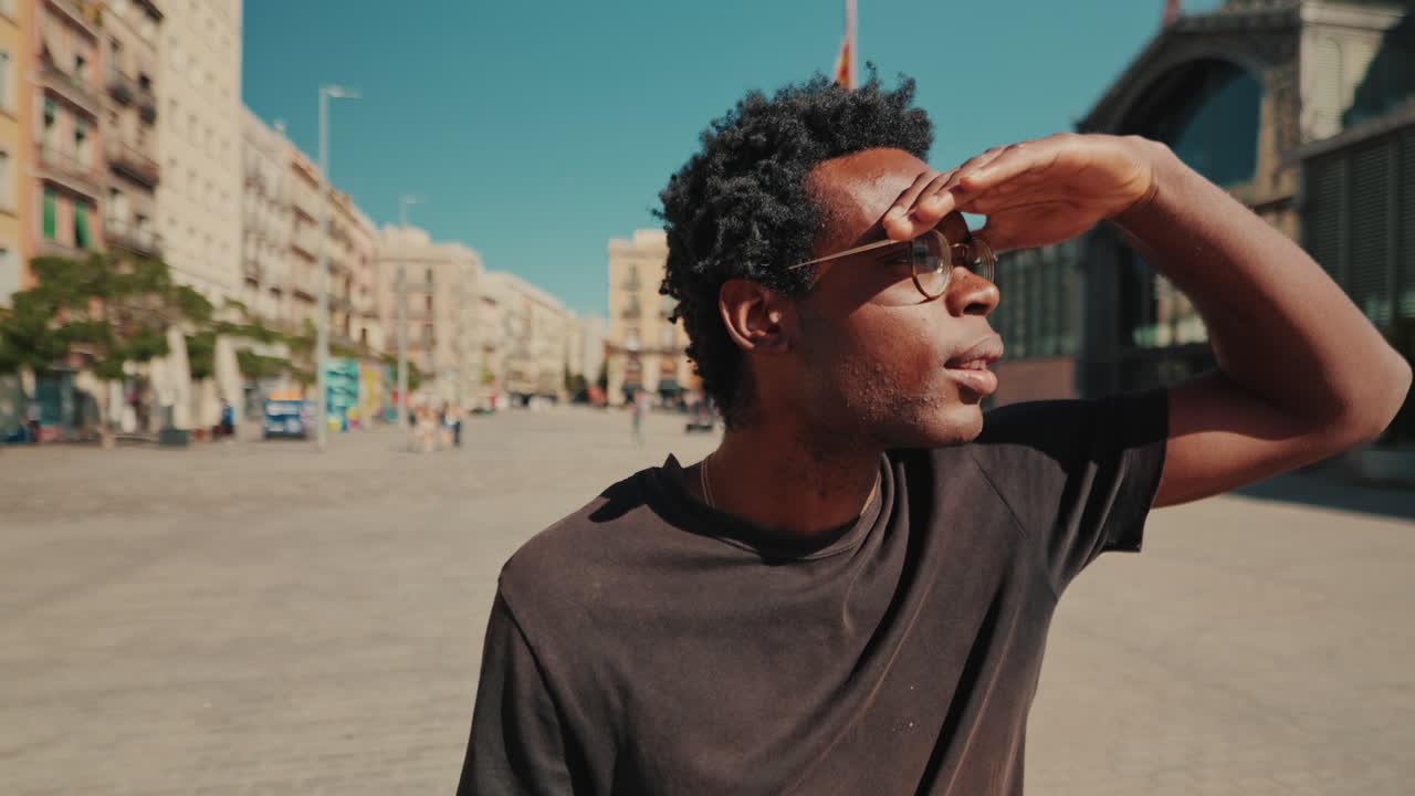 Young African American Man Looking Around in Sunny City Square