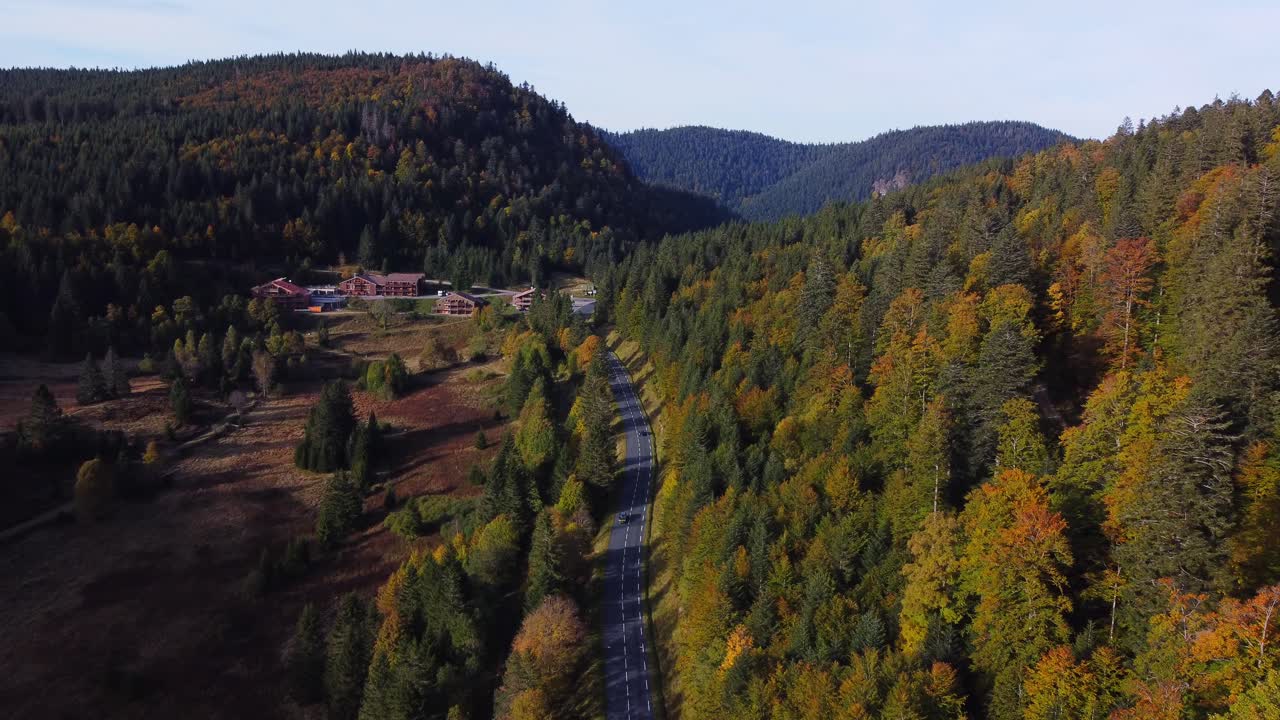 hermosa vista aérea de un paisaje montañoso rodeado de bosques de follaje de otoño y una carretera durante la temporada de otoño