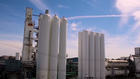 Industrial-silos-along-with-a-blue-and-cloudy-sky-in-the-middle-of-the-day