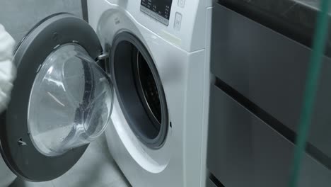 woman gets clean laundry out of washing machine. female hands getting clean clothes out of dryer