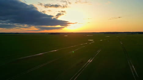 Drone-Aéreo-Del-Horizonte-De-La-Puesta-Del-Sol-Disparado-En-El-Tren-Ferrocarriles-Vacíos-Campos-Agrícolas-Esperanza-Y-Escena-Divina,-Paisaje-Cinematográfico-En-Cámara-Lenta-De-Primer-Nivel