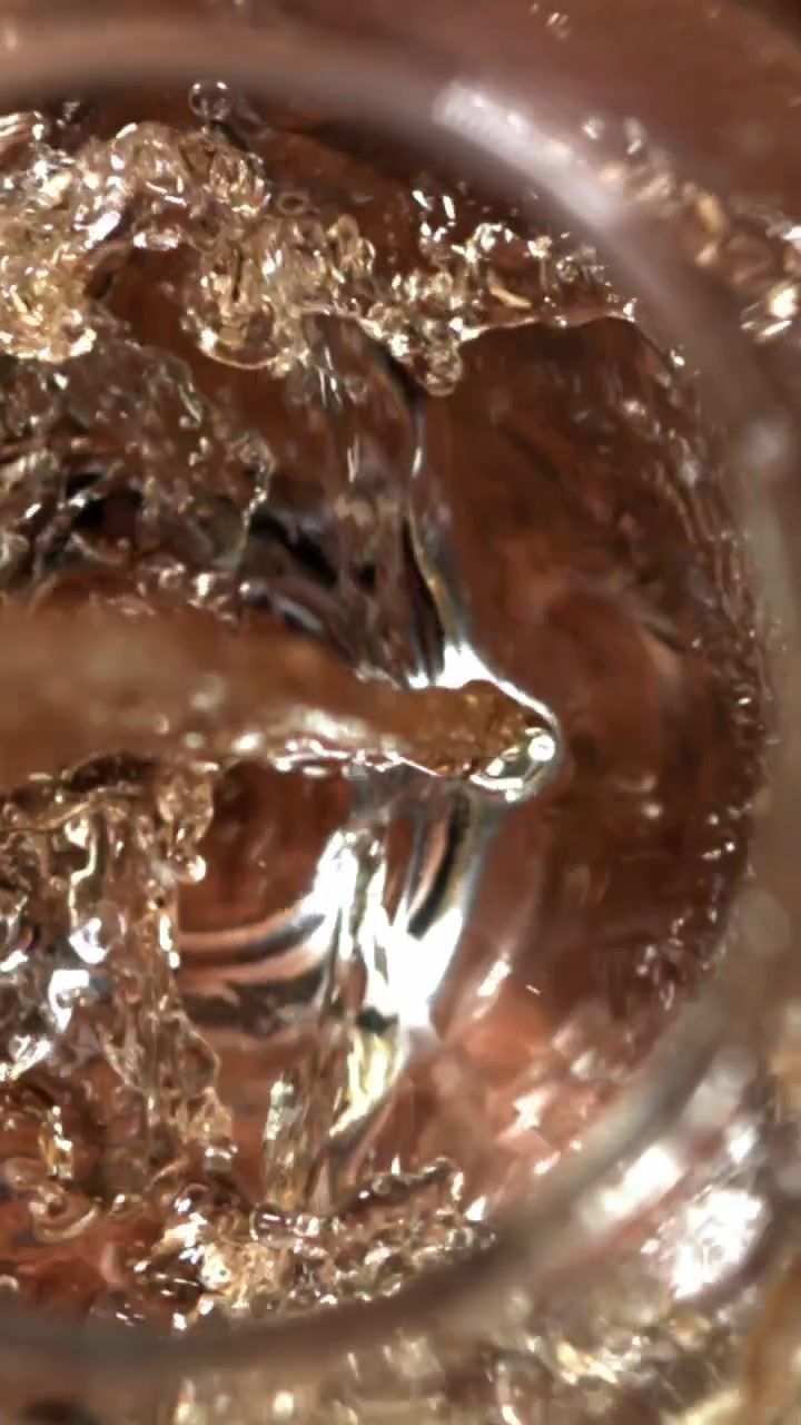 Primo piano di liquido dorato che si versa in un bicchiere