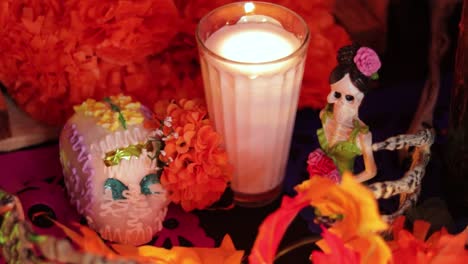 altar del día de los muertos con decoraciones de esqueletos y vela ardiente