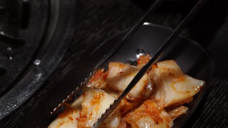 cutting korean kimchi with scissors and tongs - close up