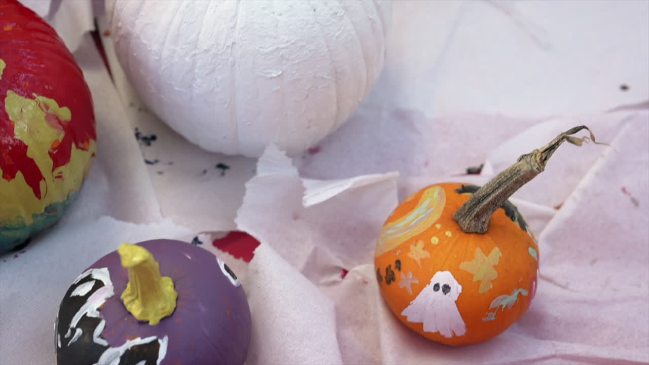 Vibrant close-up of artistically painted miniature pumpkins, adorned with spooky designs. Bright colors and intricate details evoke a festive Halloween atmosphere