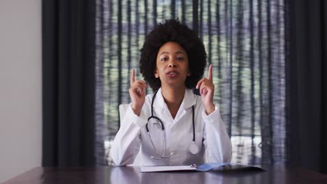 Doctora-Afroamericana-Hablando-Por-Videollamada-Mientras-Está-Sentada-En-Casa