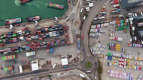 large container ship docked at hong kong commercial port, top down aerial view including stacks of shipping containers on a holding platform