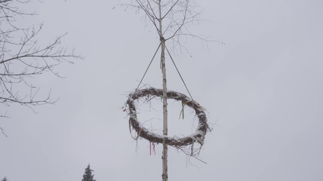 Raised maypole celebrating pagan gods in winter. Falling snow on a cold day. Prehistoric Czech village