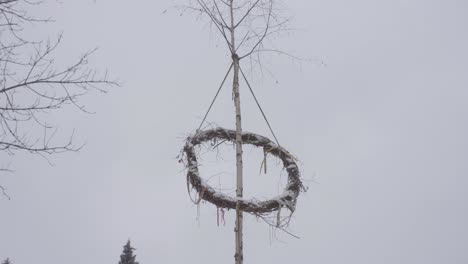 raised maypole celebrating pagan gods in winter. falling snow on a cold day. prehistoric czech village
