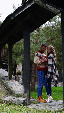 couple in love in the countryside. date of a romantic couple near the wooden gate of the cottage in autumn time. vertical video