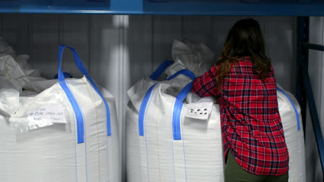 Rear-view-of-caucasian-female-worker-checking-packed-goods-in-warehouse-4k