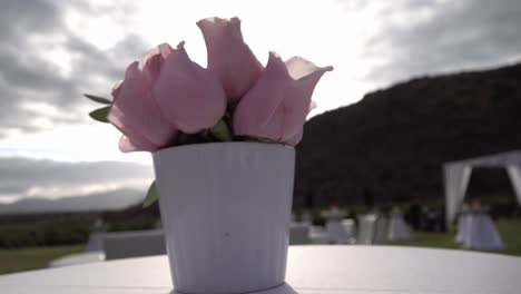 a white vase with pink roses on a table