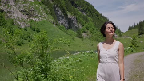 brunette model walking along river in idyllic swiss mountains. sunny summer day in switzerland. close up tracking slow motion.