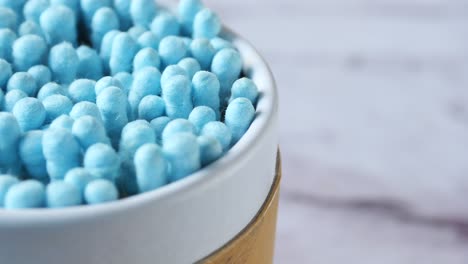 primer plano de hisopos de algodón azules en un recipiente