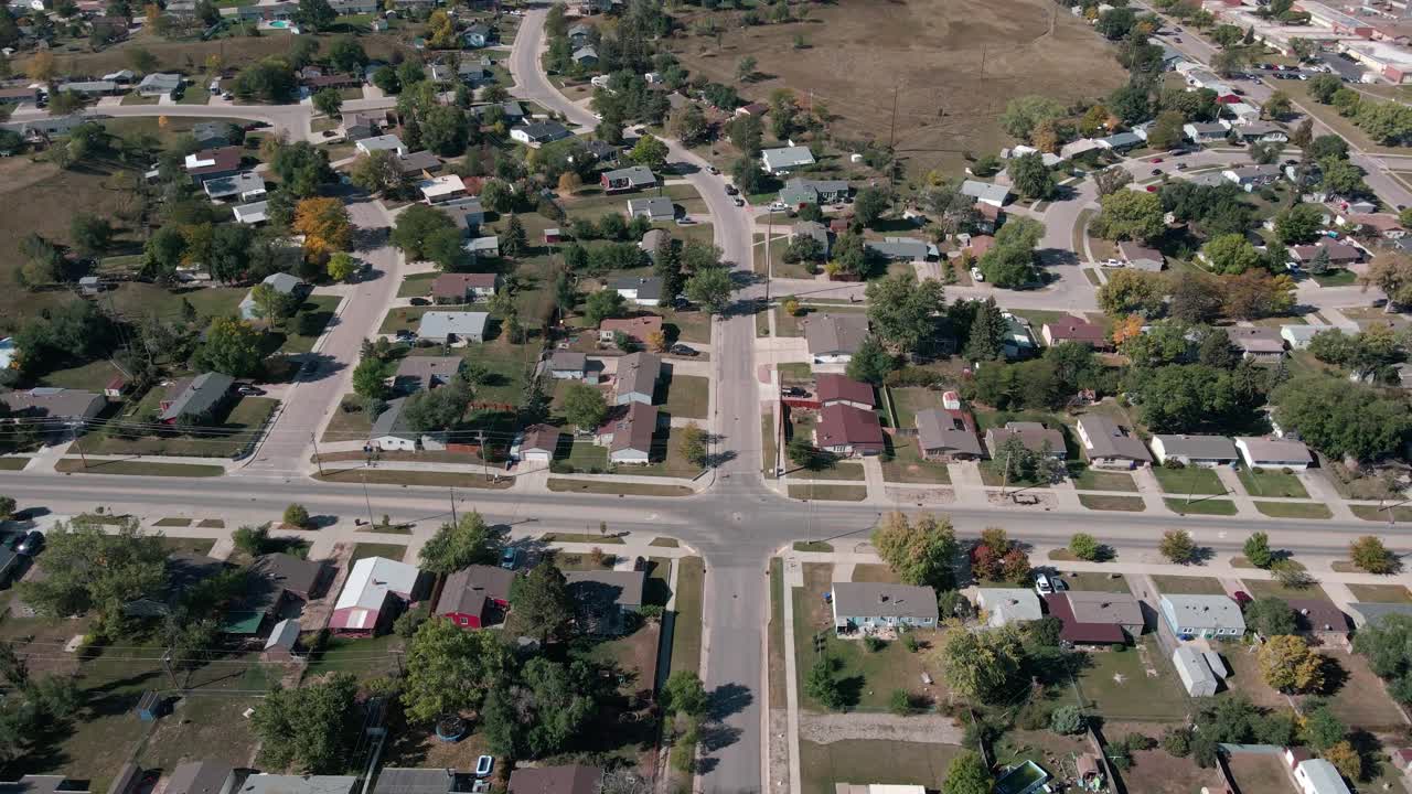 A drone flying backwards and panning the camera up revealing homes with hills in the background in Rapid City, South Dakota
