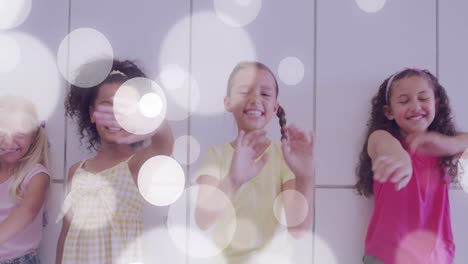 animation of white bokeh spots over happy diverse schoolgirls waving by lockers