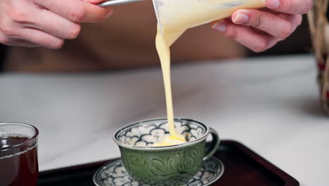 barista pouring whipped egg york into ceramic cup