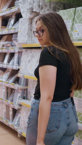 vista trasera de una compradora caminando por el pasillo del centro comercial, llevando bolsas de compras mientras mira los productos en el estante, el cabello largo fluye mientras se mueve en un entorno minorista bien iluminado