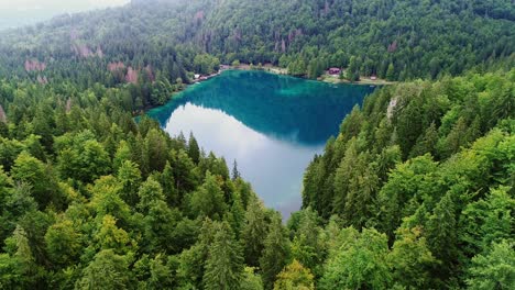 lago di fusine lake glows with deep blue shades amid lush forest in italian alps