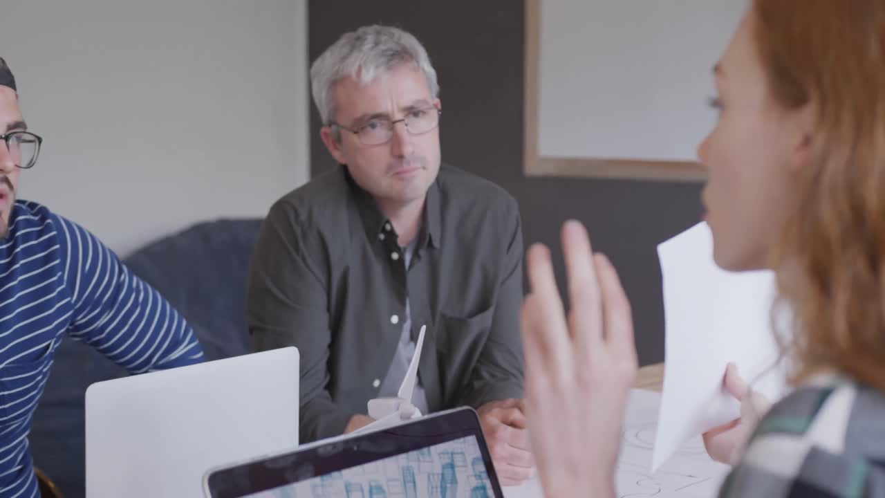 dos hombres y una mujer caucásicos trabajando en una oficina creativa