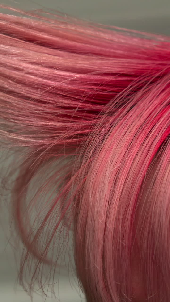 Primo piano di capelli rosa vivace mentre vengono pettinati.