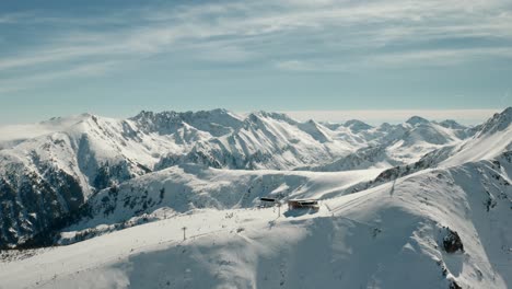 ski resort chairlift atop snowy mountaintop in europe alps, aerial